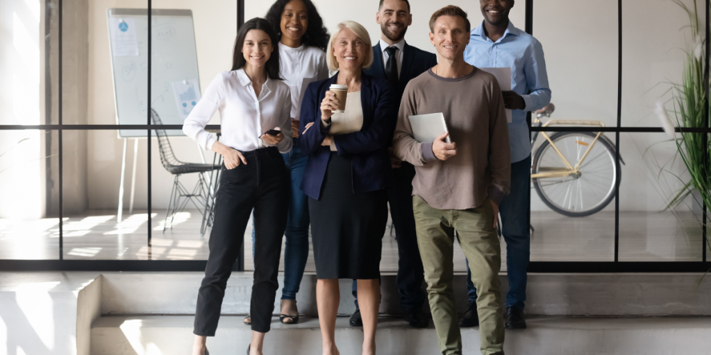 Group of diverse professionals standing together in a modern office, representing full-time employee placement and teamwork for organizational growth.